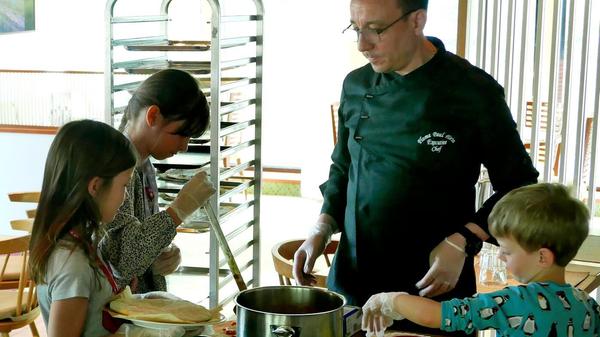 Im Restaurant macht der Chefkoch mit den Kindern Pizza.