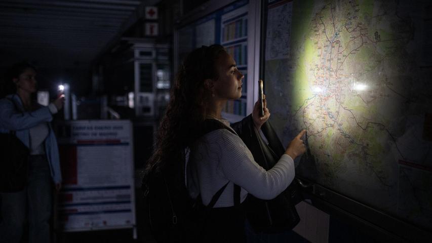 Eine Frau behilft sich mit der Taschenlampe ihres Handys, um den Plan des Madrider U-Bahn-Netzes anschauen zu können. Eine Frau behilft sich mit der Taschenlampe ihres Handys, um den Plan des Madrider U-Bahn-Netzes anschauen zu können.