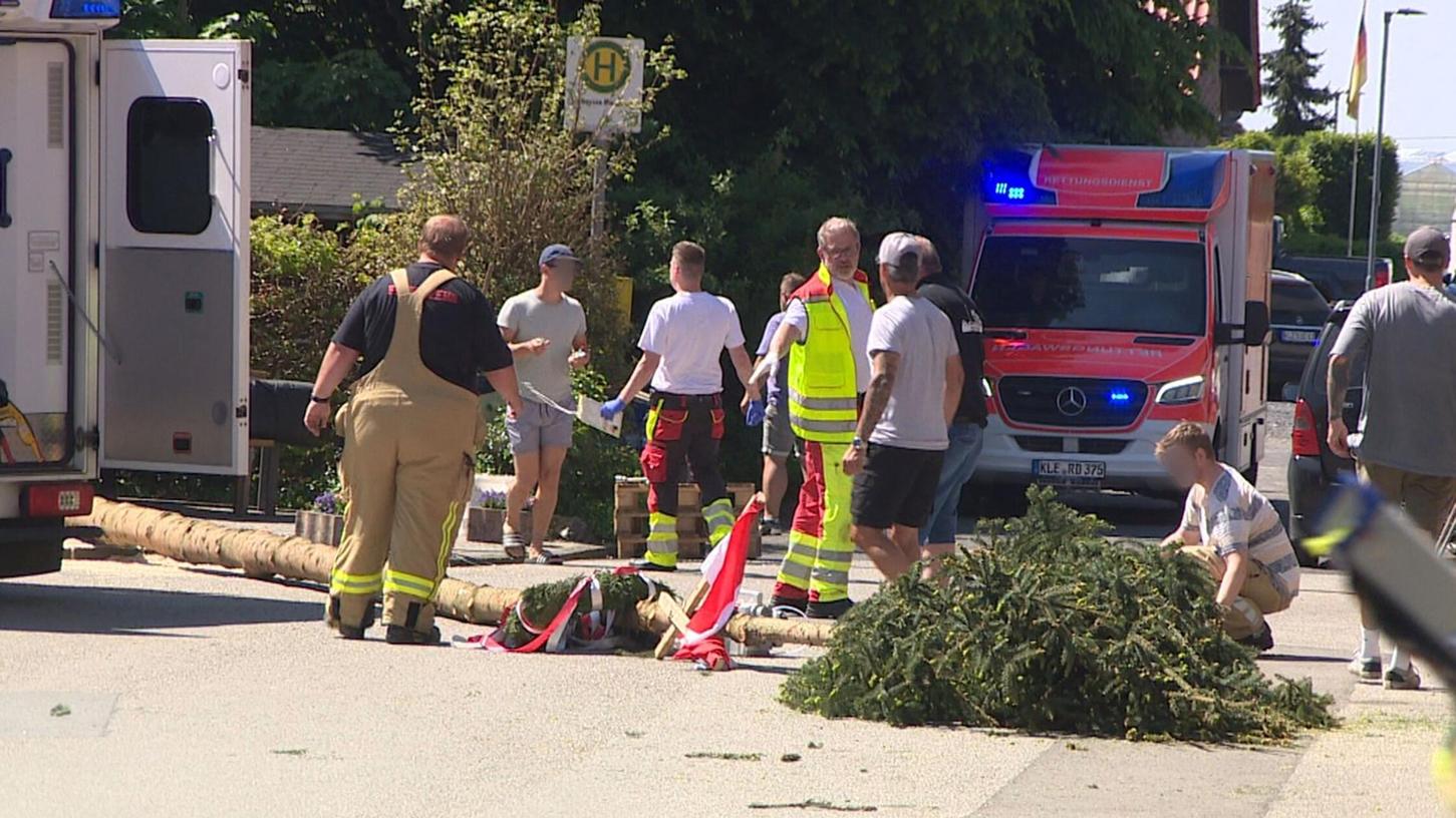 Der umgestürzte Maibaum liegt auf der Straße vor einem Einsatzwagen der Feuerwehr. Der umgestürzte Maibaum liegt auf der Straße vor einem Einsatzwagen der Feuerwehr.