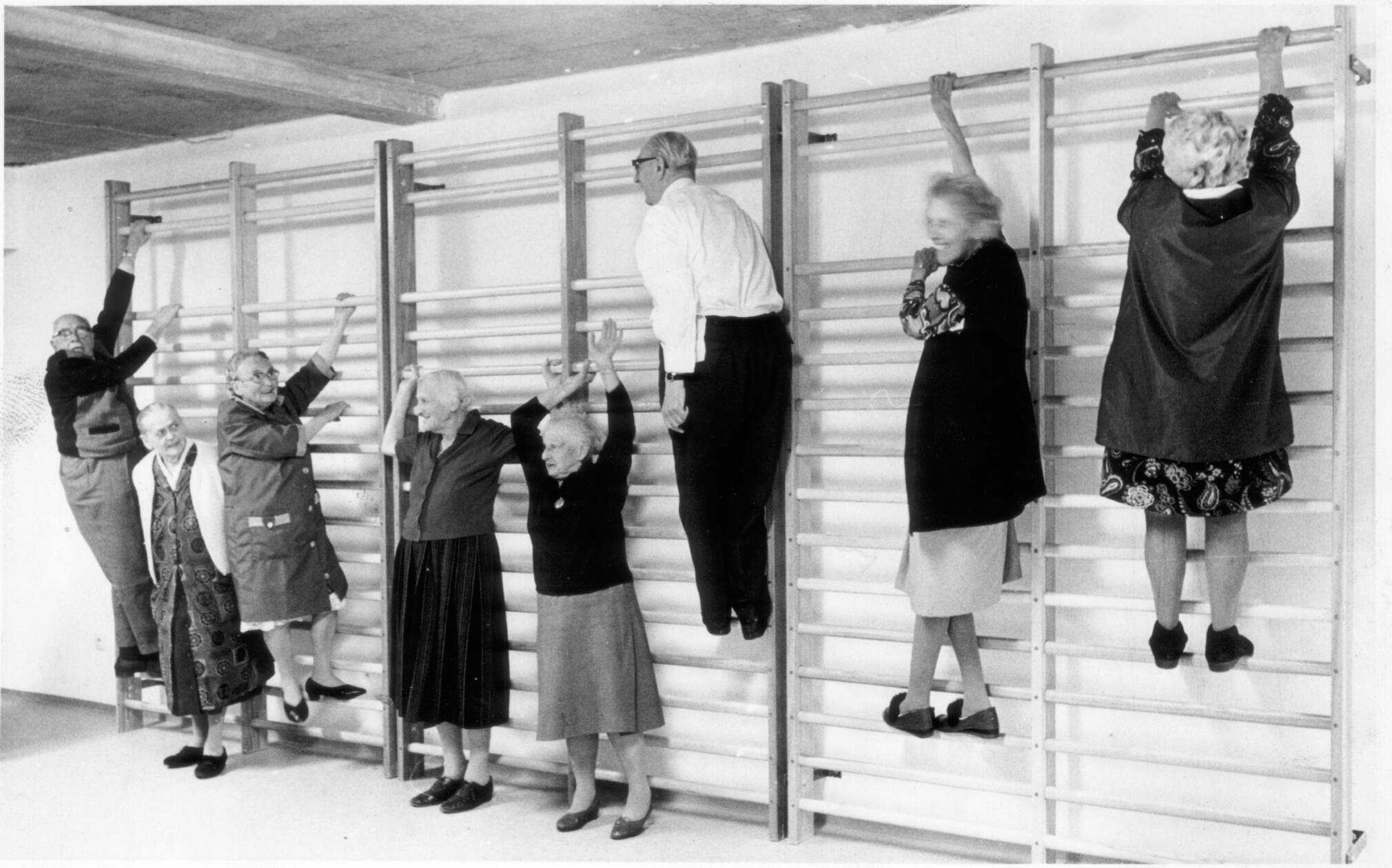 Seniorensport im Jahre 1972: Im Julius-Bauer-Heim am Thoner Weg, welches später durch das Hephata Pflegezentrum in Schafhof ersetzt wurde, stand alles im Zeichen der Rehabilitation. Die Bewohner sollten wieder fit für einen selbstständigen Alltag gemacht werden. Hierfür verfügte das Haus über Bäder, Massagen und Bewegungstherapie-Angebote, auch die hier abgebildete Sprossenwand gehörte dazu. Zum Teil mit sichtlichem Spaß erklommen die betagten Sportler und Sportlerinnen das Holzgerüst. Auch ein Bierstüberl mit Kegelbahn sollte Aktivität und Wohlbefinden steigern, leider ist uns hierzu jedoch kein Bildmaterial überliefert.