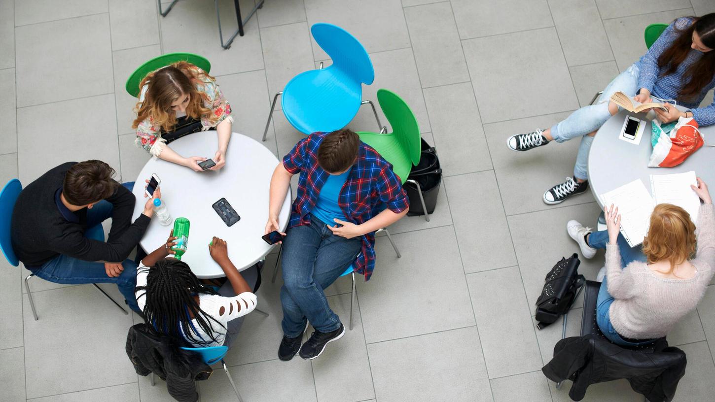 Mehrere Personen sitzen in einer Cafeteria. Mehrere Personen sitzen in einer Cafeteria.