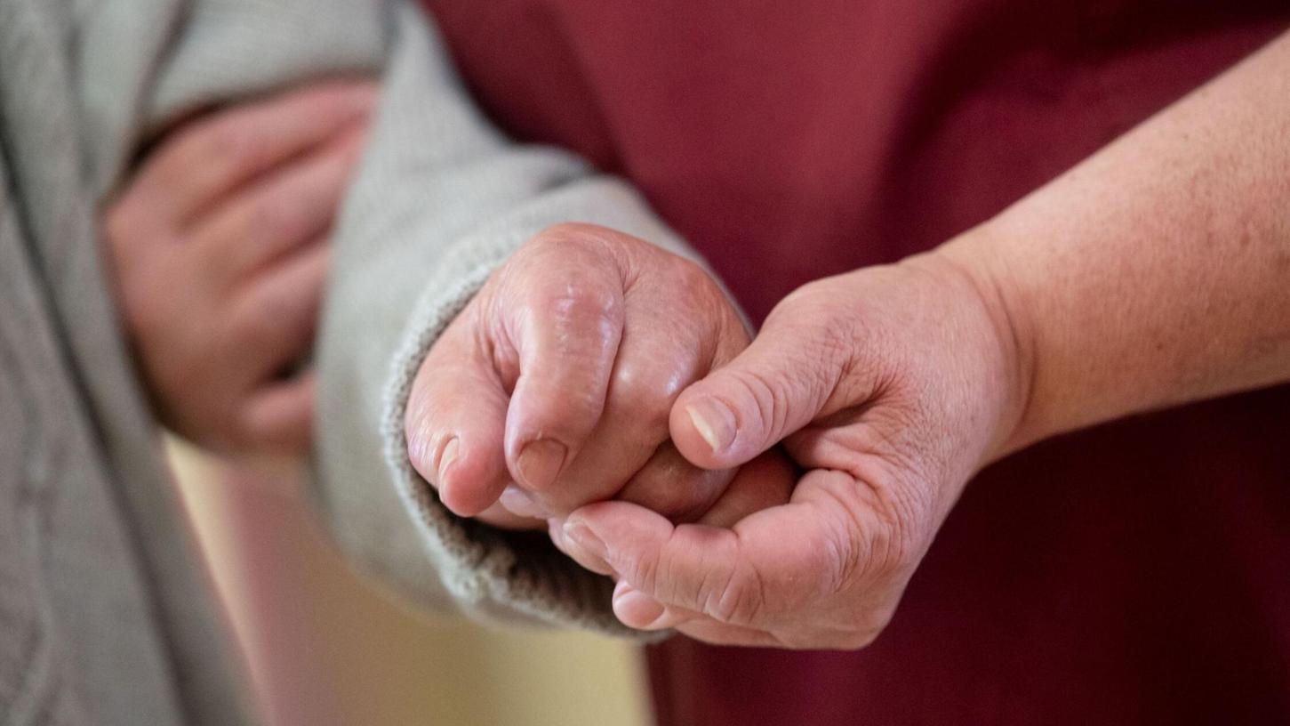 Eine Pflegekraft betreut in einem Seniorenhaus einen Bewohner. Eine Pflegekraft betreut in einem Seniorenhaus einen Bewohner.