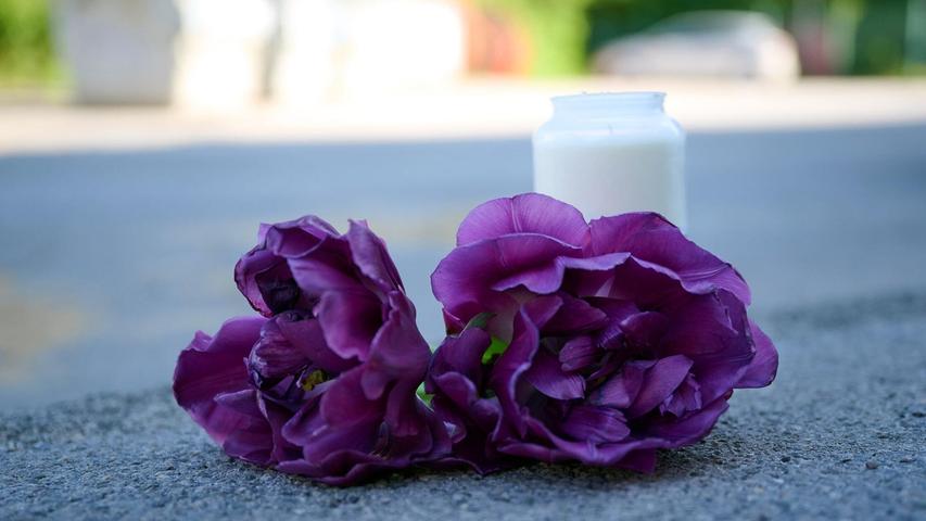 Blumen und eine Kerze liegen auf einem Schotterplatz vor dem Eingang zum Spielplatz, auf dem in der Nacht ein 17-Jähriger einen 14-Jährigen erstochen haben soll. Blumen und eine Kerze liegen auf einem Schotterplatz vor dem Eingang zum Spielplatz, auf dem in der Nacht ein 17-Jähriger einen 14-Jährigen erstochen haben soll.