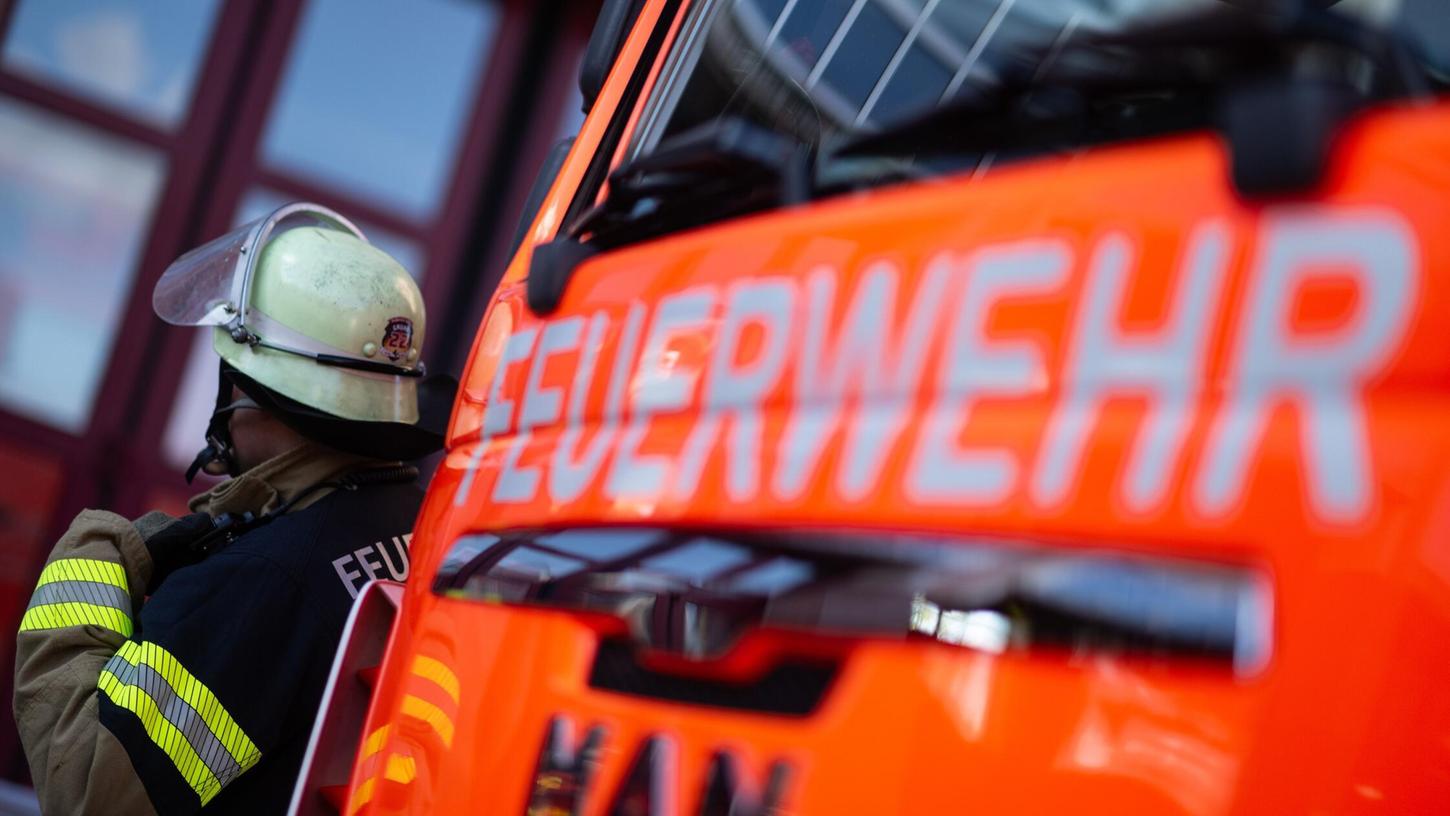 Eine Einsatzkraft der Feuerwehr steht neben einem Einsatzfahrzeug der Feuerwehr. (Symbolbild) Eine Einsatzkraft der Feuerwehr steht neben einem Einsatzfahrzeug der Feuerwehr. (Symbolbild)