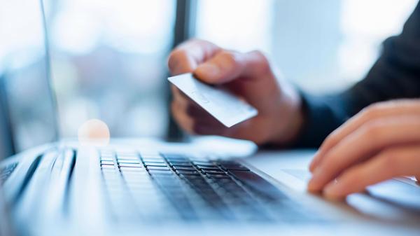 Hand holding a credit card over a laptop for onlin