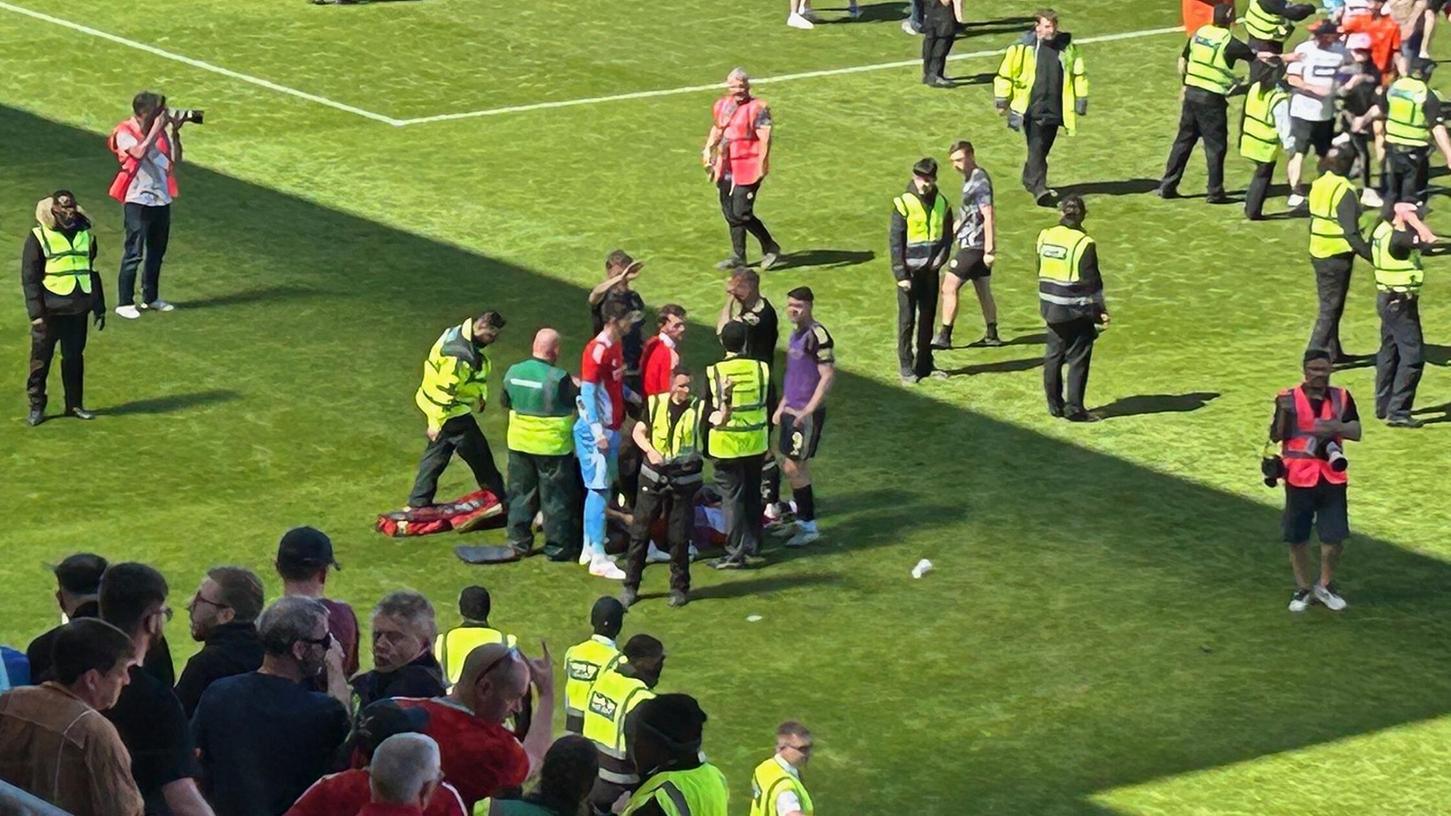 Jack MacKenzie von Aberdeen wird auf dem Spielfeld behandelt, nachdem er von einem Gegenstand getroffen wurde. Jack MacKenzie von Aberdeen wird auf dem Spielfeld behandelt, nachdem er von einem Gegenstand getroffen wurde.