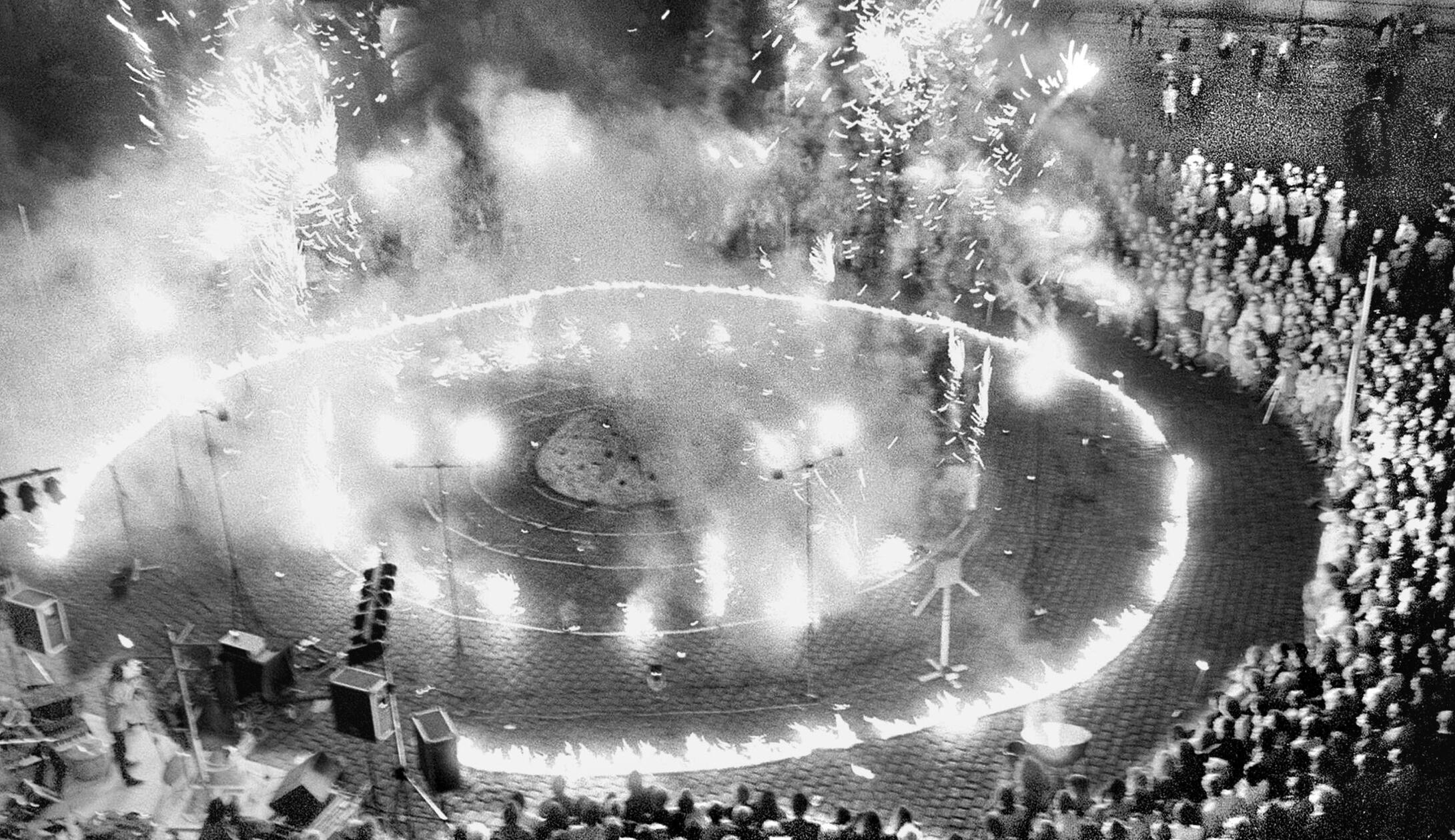 „Moonlanding und Blaukraut“ war der Titel dieser pyrotechnischen Schau von Götz Schwörer. Am 23.6.1990 eröffnete er damit fulminant die Ausstellung „Zehnvorzweitausend“ der Künstlergruppe „Der Kreis“ auf dem Hauptmarkt in Nürnberg. Das Feuerspektakel untermalte ein Percussionist mit wildem Hämmern auf Alltagsmaterial wie Waschmaschinentrommeln und metallenen Kleiderständern. Als die Schwefelschwaden abgezogen waren, konnten die Zuschauer den Kunst-Parcours, der direkt zwischen den Marktständen aufgebaut war, erkunden. Zehn Tage lang sorgten die Skulpturen und Installationen zwischen Obst und Gemüse für Kontroversen.