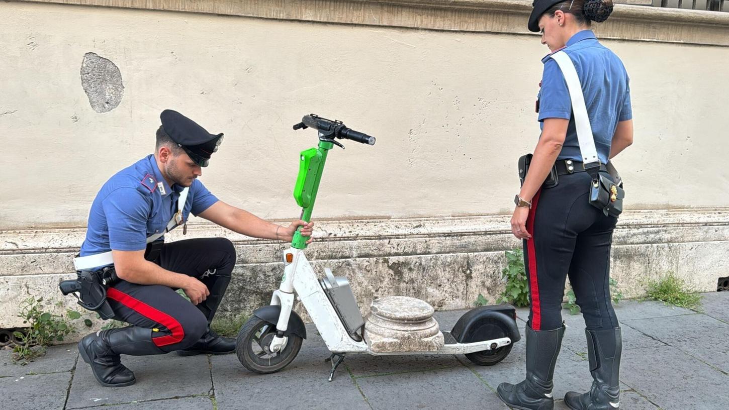 Zwei Carabinieri begutachten den Marmorsockel auf einem elektrischen Leihroller. Zwei Carabinieri begutachten den Marmorsockel auf einem elektrischen Leihroller.