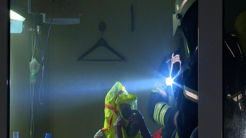 Ein Feuerwehrmann hilft einem Patienten in einem Zimmer des Krankenhauses. Ein Feuerwehrmann hilft einem Patienten in einem Zimmer des Krankenhauses.