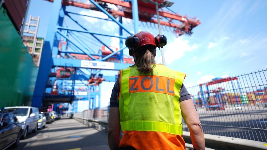 Eine Zollbeamtin steht neben einem Containerschiff im Hamburger Hafen. Eine Zollbeamtin steht neben einem Containerschiff im Hamburger Hafen.