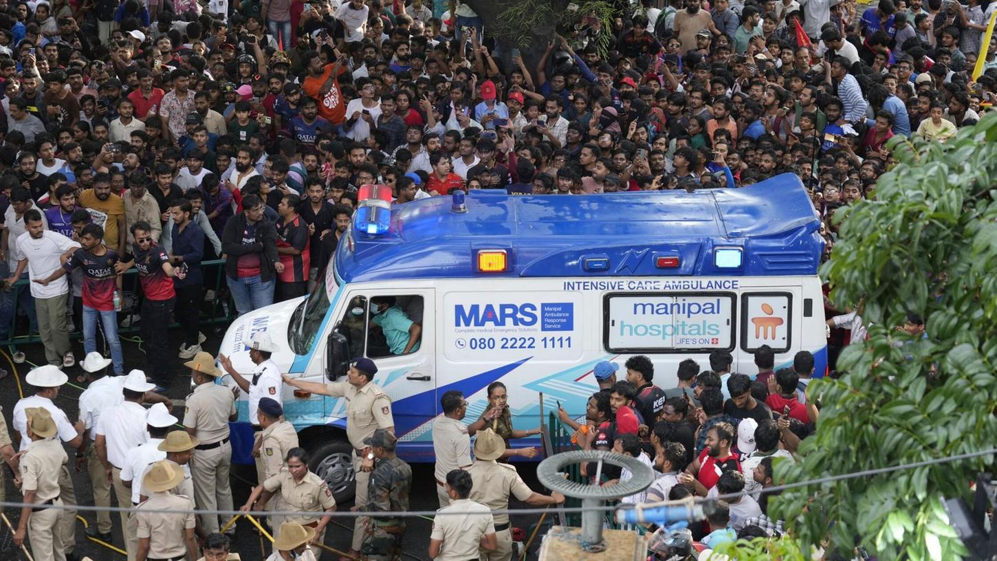 Ein Krankenwagen bahnt sich den Weg durch eine Menschenmenge am M. Chinnaswamy-Stadion in der indischen Stadt Bengaluru. Ein Krankenwagen bahnt sich den Weg durch eine Menschenmenge am M. Chinnaswamy-Stadion in der indischen Stadt Bengaluru.
