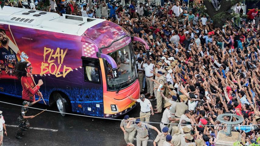 Kricket-Fans in Bengaluru jubeln ihrem Heimteam zu, das in einem Bus sitzt. Kricket-Fans in Bengaluru jubeln ihrem Heimteam zu, das in einem Bus sitzt.