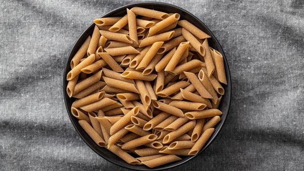 Uncooked whole grain pasta. Raw penne pasta in pla