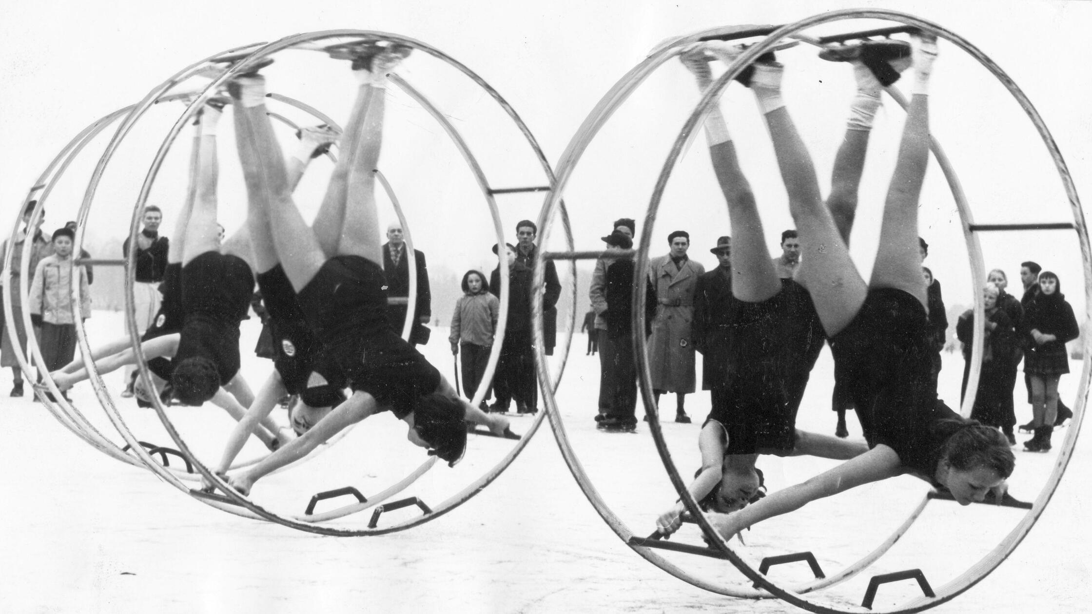 Eine staunende Menge sammelte sich im Januar 1955 auf dem zugefrorenen Dutzendteich um einige Rhönrad-Turnerinnen. Diese trainierten für ein besonders ausgefeiltes Programm auf der rutschigen Eisfläche. Im selben Jahr berichtete unsere Zeitung, dass für den Erfinder des Rhönrades, Otto Feick, eine Spendenaktion gestartet sei. Die - nach seinem späteren Wohnsitz in der Rhön benannte - Erfindung hatte ihn nicht reich werden lassen. Vielmehr war Feick auf Fürsorgeunterstützung angewiesen. Sein unverdrossenes Lebensmotto lautete „Kämpfe, ringe – aber singe!“. Es steht zu befürchten, dass die erbarmenswert dünn gekleideten Turnerinnen zum Zeitpunkt der Aufnahme dagegen nur mit den Zähnen klappern konnten.