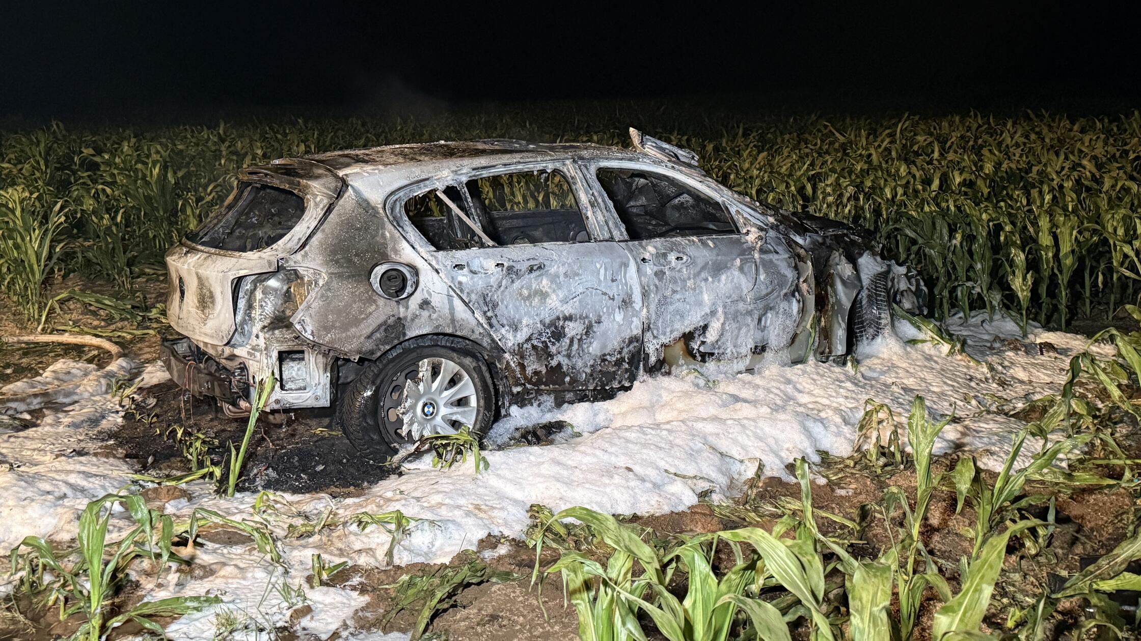 Flammen in der Nacht, ein zerstörter Wagen – und e