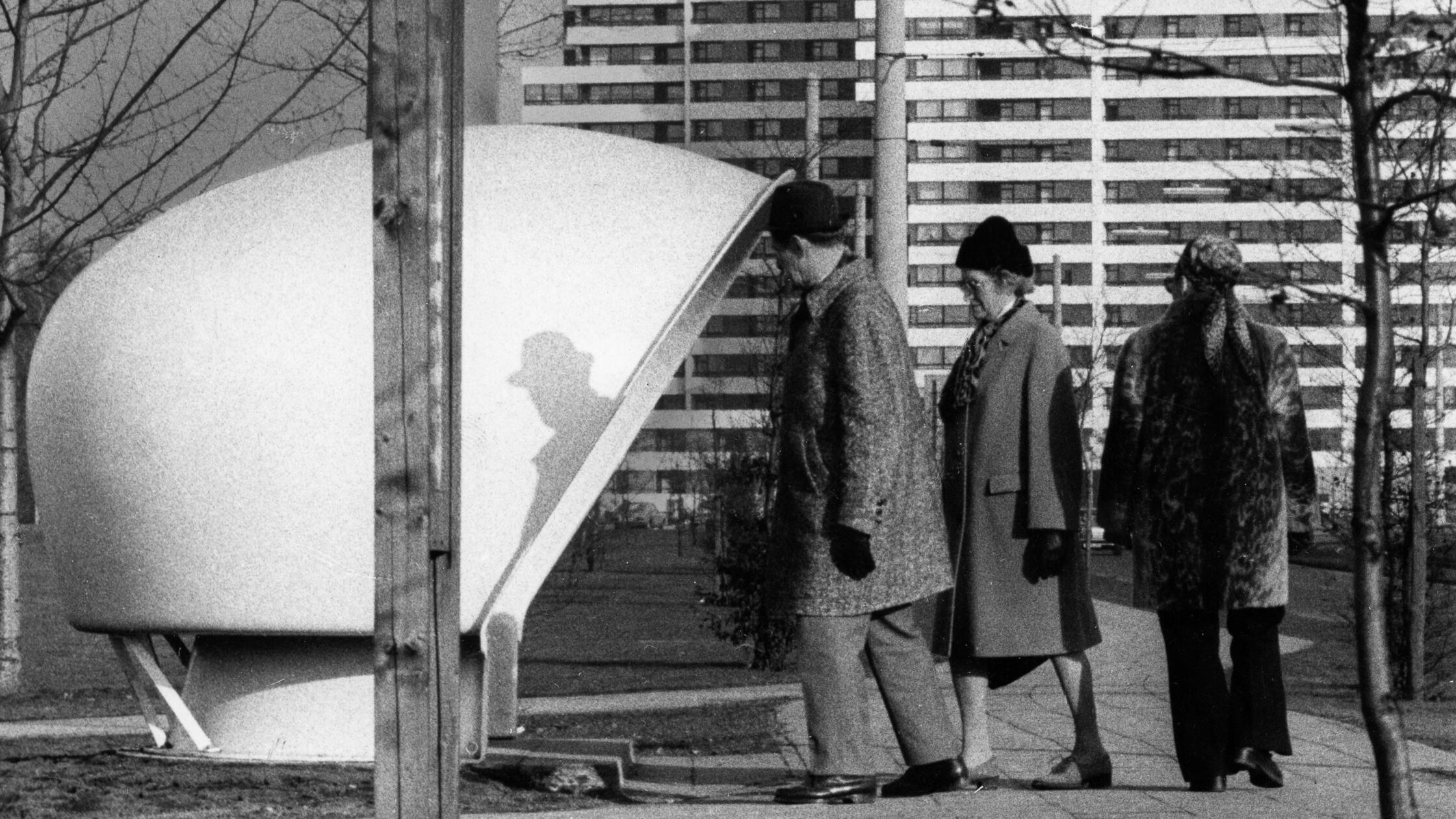 Futuristisch mutete dieser Wartehäuschen-Prototyp bei der Bushaltestelle an der Nürnberger Ostendstraße an. Der optisch an ein Iglu erinnernde Unterstand nach einem Entwurf des Dänen Poul Cadovius entsprach der bisweilen eigenwilligen Formsprache der späten 1960er und 1970er Jahre. Auf einer im Inneren ringsum verlaufenden Bank sollten nach Erwartung der VAG acht bis zehn Personen Platz finden. Wegen seiner bis auf 1,9 Meter heruntergezogenen Dachkante war der Zugang für groß gewachsene Fahrgäste jedoch nur bedingt geeignet, wie unser Foto deutlich zeigt.