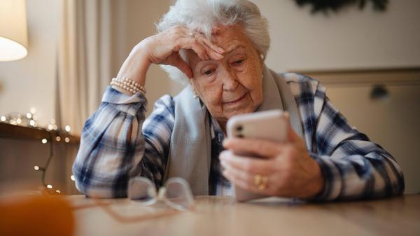 Elderly woman struggling to use smartphone, lookin