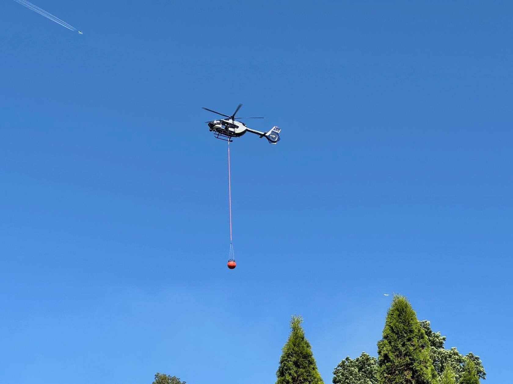 Ein Hubschrauber der Polizei bringt Löschwasser zur Einsatzstelle.