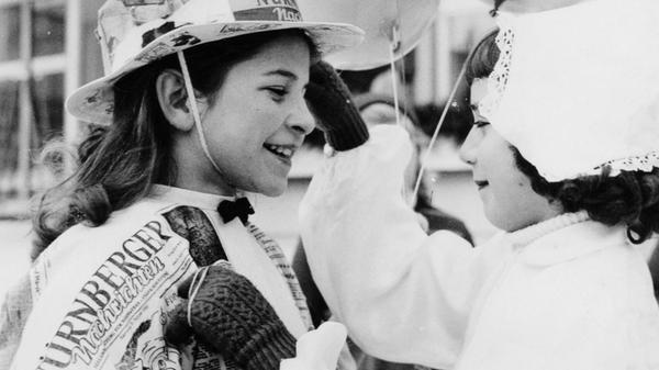 Beim Eisfasching im Januar 1955 wird ein Mädchen mit einem Kostüm aus Zeitungspapier der Nürnberger Nachrichten von einer kleinen „Holländerin“ bestaunt. Wo heute das Einkaufszentrum Mercado in Nürnberg steht, war bis zum Jahr 2001 das Linde-Eisstadion. Jeden Mittwoch in der Faschingszeit durften Kinder dort kostümiert auf der Eisfläche herumsausen. Bei kleinen Wettbewerben, wie Eierlauf auf Schlittschuhen, konnten sie etwas Süßes gewinnen, und es gab natürlich auch eine Masken-Prämierung. Im Mittelpunkt des fröhlichen Treibens war stets ein Schlittschuhfahrer im Eisbärkostüm, gestellt vom Linde-Stadion selbst, der immer eine Schar Kinder an seinem zottigen Fell hinter sich herzog und sie geduldig auf seinem Rücken reiten ließ.