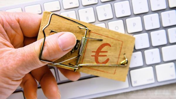 Hand in Mausefalle mit Euro-Zeichen vor einer Comp