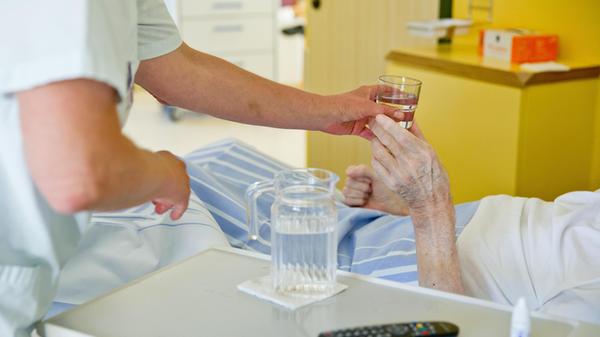 Krankenpflegerin gibt Patienten Wasser