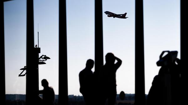 Passagiere schauen am Flughafen einem startenden F