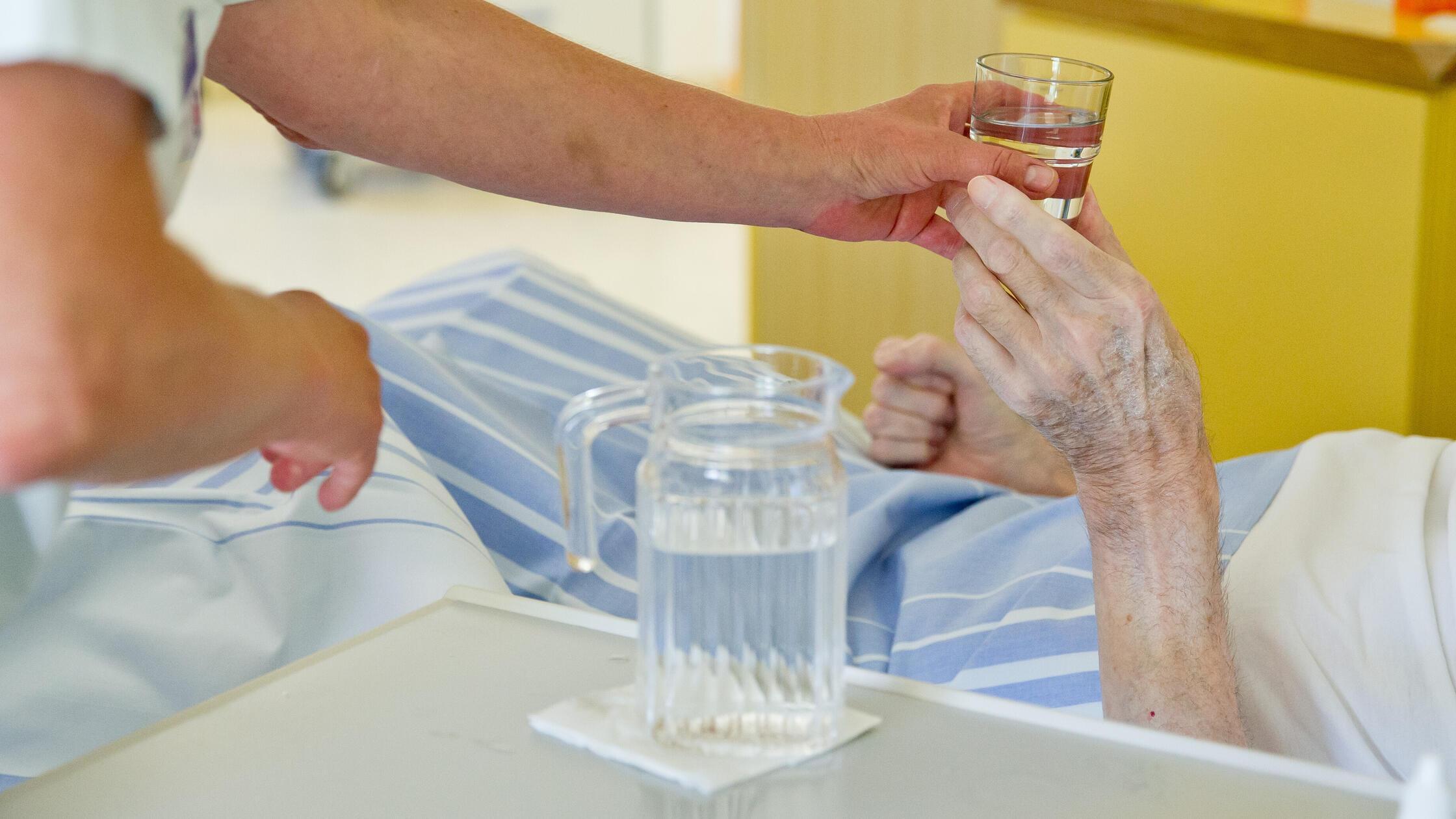 Krankenpflegerin gibt Patienten Wasser