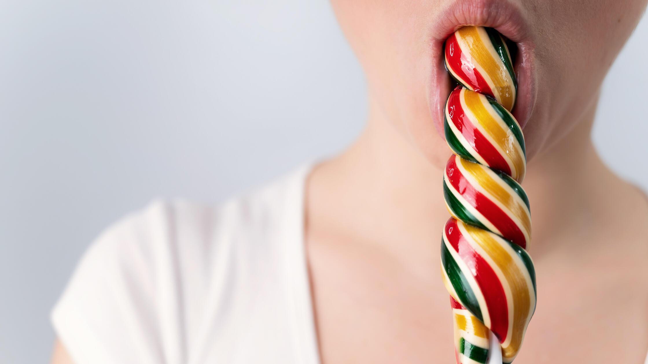 Close-up portrait of a woman sucking a long lollip