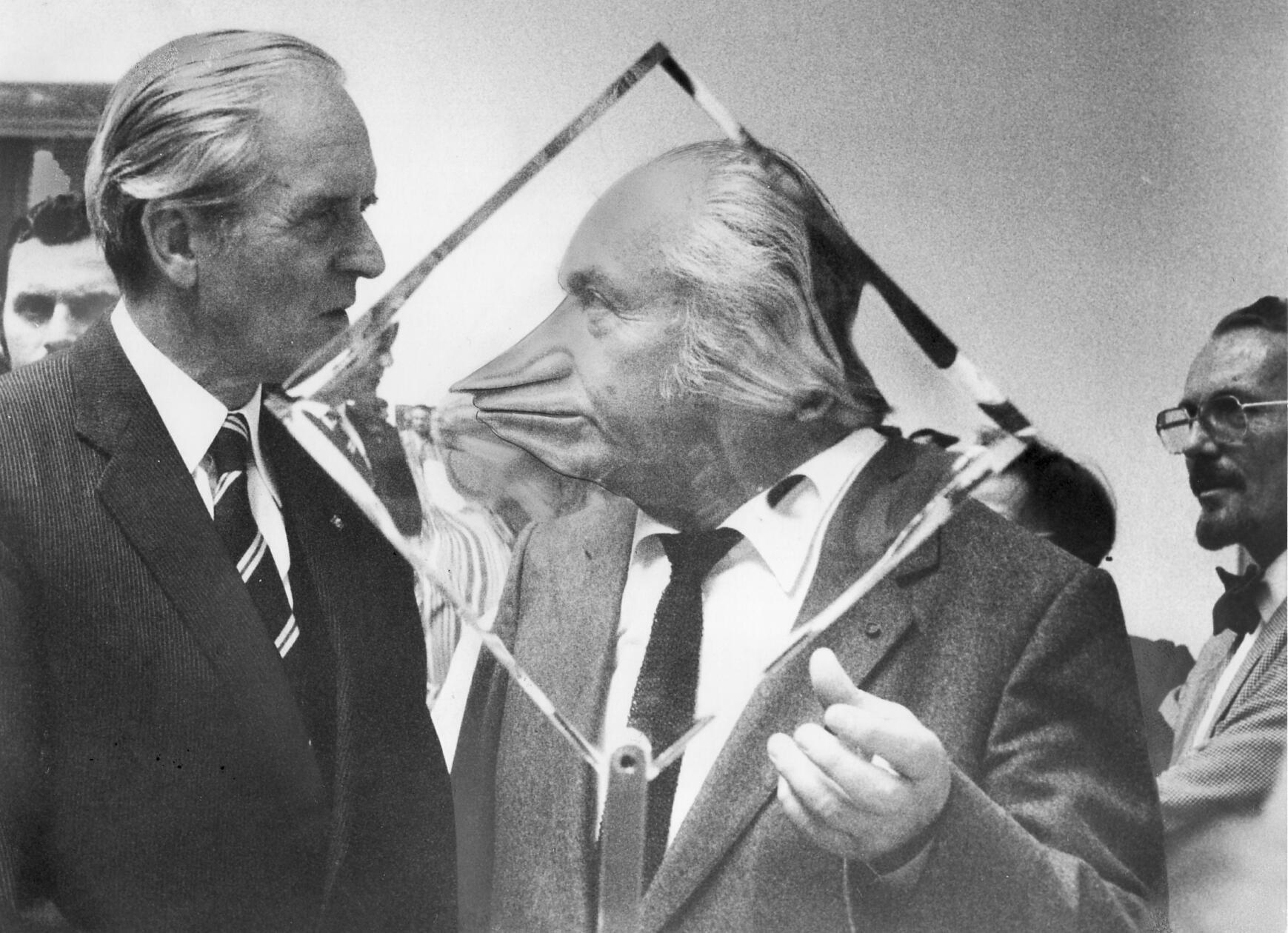 Dass Museumsdirektoren als surreale Kunstwerke fungieren können, bewies im September 1981 im Rahmen der 29. Jahresausstellung des Deutschen Künst­lerbundes in Nürnberg humorvoll der damalige Direktor der Kunsthalle, Curt Heigl. Während er sich mit dem zur Eröffnung angereisten damaligen Bundespräsi­denten Karl Carstens (links) unterhielt, stand er hinter einem spezialgeschliffenen gläsernen Ausstellungsobjekt des Künstlers Victor Bonato. Schon 1968 hatte der Deutsche Künstlerbund zuvor mit seiner Jahresausstellung einmal Nürnberg beehrt. Damals hatte Joseph Beuys für Irritation gesorgt, als er im Künstlerhaus die Installationen „Fettecke“ und „Luftpumpen mit Fett“ zeigte. Bei der Ausstellung im Jahr 1981 ging es deutlich fettärmer zu.