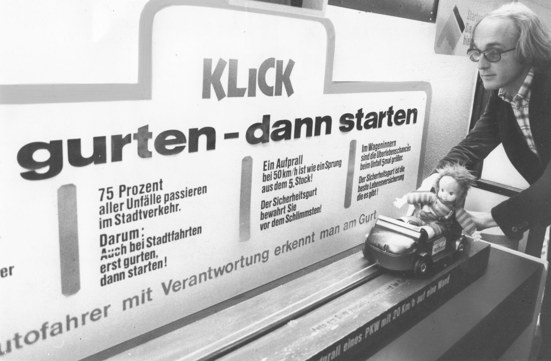 Die Darbietung dieses verspielten Mini-Crash-Tests sollte im Oktober 1974 die Gurtmuffel Nürnbergs eines Besseren belehren. Seit dem 1. Januar jenes Jahres mussten alle in der BRD neu zugelassenen Pkws mit Dreipunktegurten für die Vordersitze ausgestattet sein. Das Verkehrsministerium startete eine Kampagne, um vom Sinn des Gurts zu überzeugen. Ihr sperriger Slogan "Erst gurten - dann starten" wurde nach kurzer Zeit mit "Erst gurten - dann spurten" in geschmeidige Reimform gebracht. Trotz aller Bemühungen blieb der Spurt ohne Gurt aber weit verbreitet. 1976 wurde das Anschnallen auf den Vordersitzen Pflicht, auf den Rücksitzen erst 1984. Ebenfalls 1984 erfolgte ein Bußgelderlass, der für deutlich mehr Klicks vor der Abfahrt sorgte.