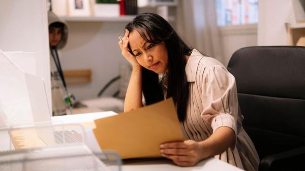 Stressed womanworking at home office reading docum
