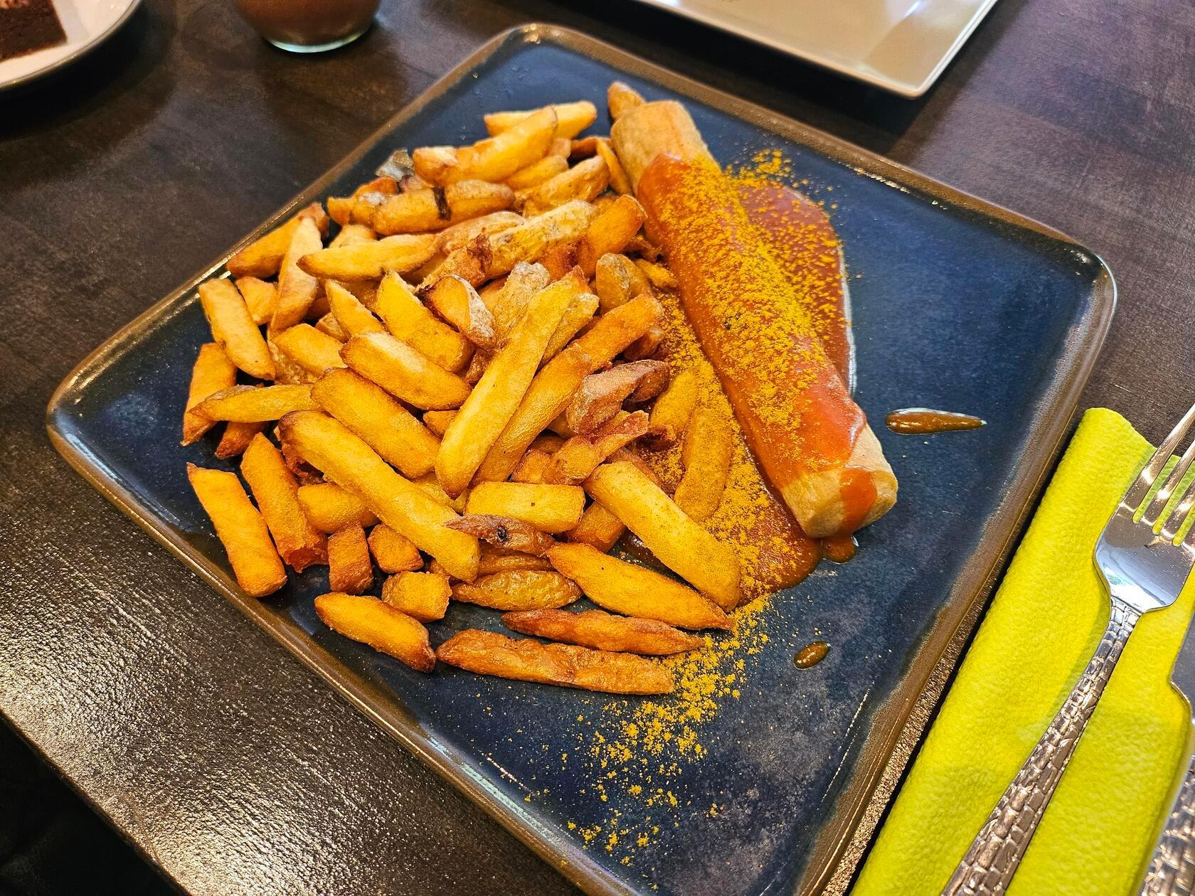 Platz 12: Philipp Nagel serviert in seinem Restaurant Heartcore Kitchen Burger, Burrito und auch Currywurst mit Pommes. Wie die Speisekarte Tag für Tag aussieht, erfahren Sie auf Instagram oder vor Ort, denn der Inhaber möchte seine Gäste mit viel Abwechslung überzeugen. Im Restaurant in der Fürther Straße 9A gibt es ebenfalls einige vegane Gerichte. Die Currywurst schafft es in unserem Voting auf den 12. Platz.