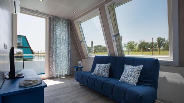 Wenn man die Vorhänge aufzieht, hat man im Inneren der klimatisierten Hausboote oft faszinierende Ausblicke auf das Wasser, den Garten und die anderen bunten Häuschen.