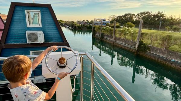 Auf dem Sonnendeck kann man die Wärme genießen, den Abend entspannt ausklingen lassen – oder auch mal Kapitän spielen. Rechts im Hintergrund sieht man die "Emerald River", das Restaurantschiff auf dem Tagliamento, auf dem Frühstück und Abendessen serviert werden.