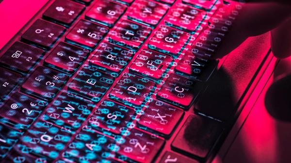 Close-up of a hand typing on a laptop keyboard wit