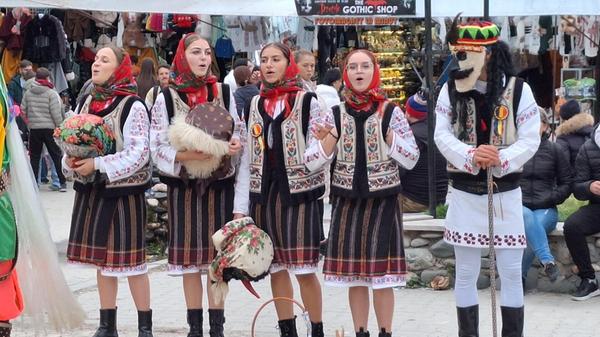 Die Sängerinnen tragen Tracht, die Männer Masken.