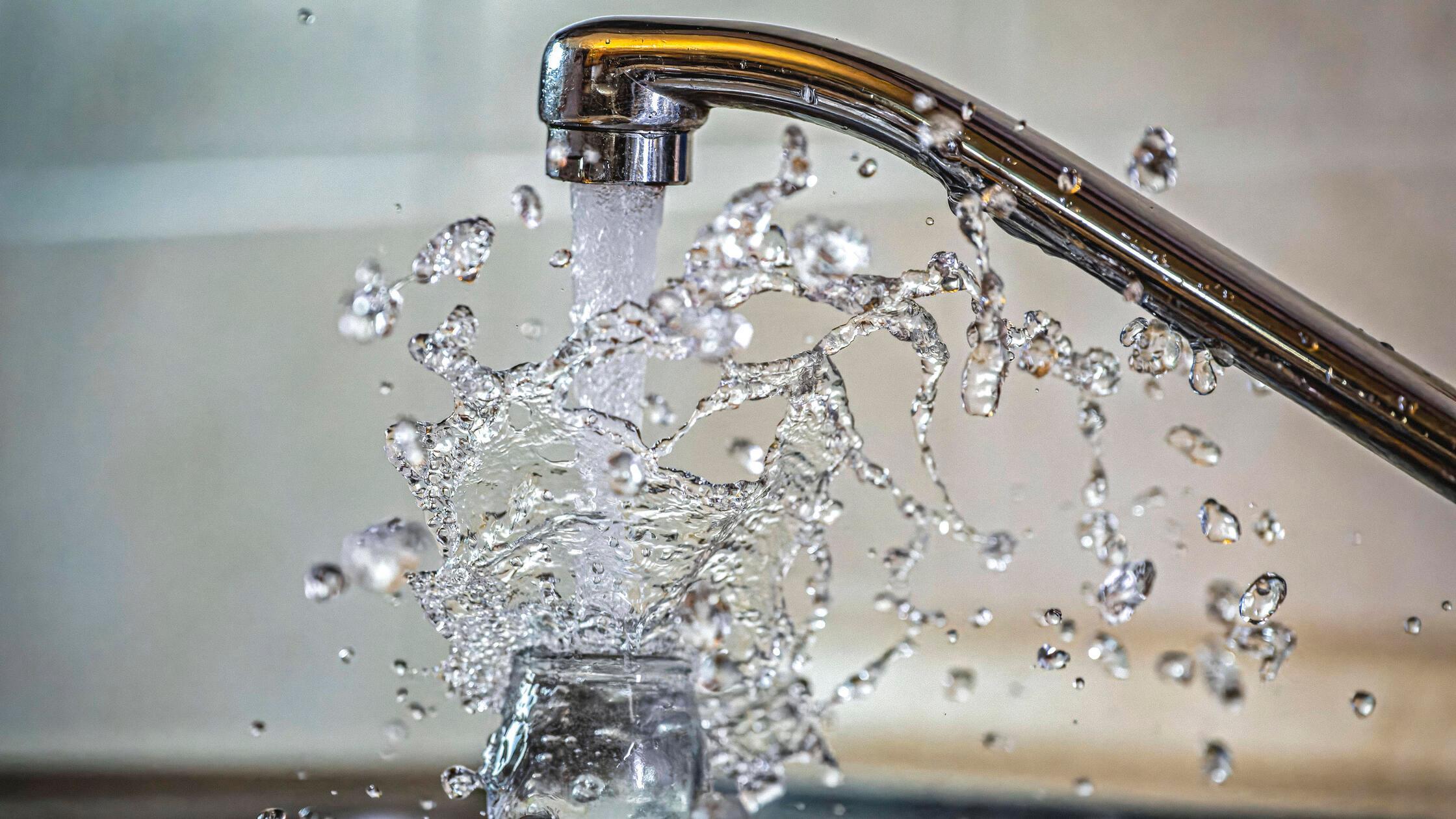 03.01.2024, Wasser spritzt aus dem Wasserhahn in e