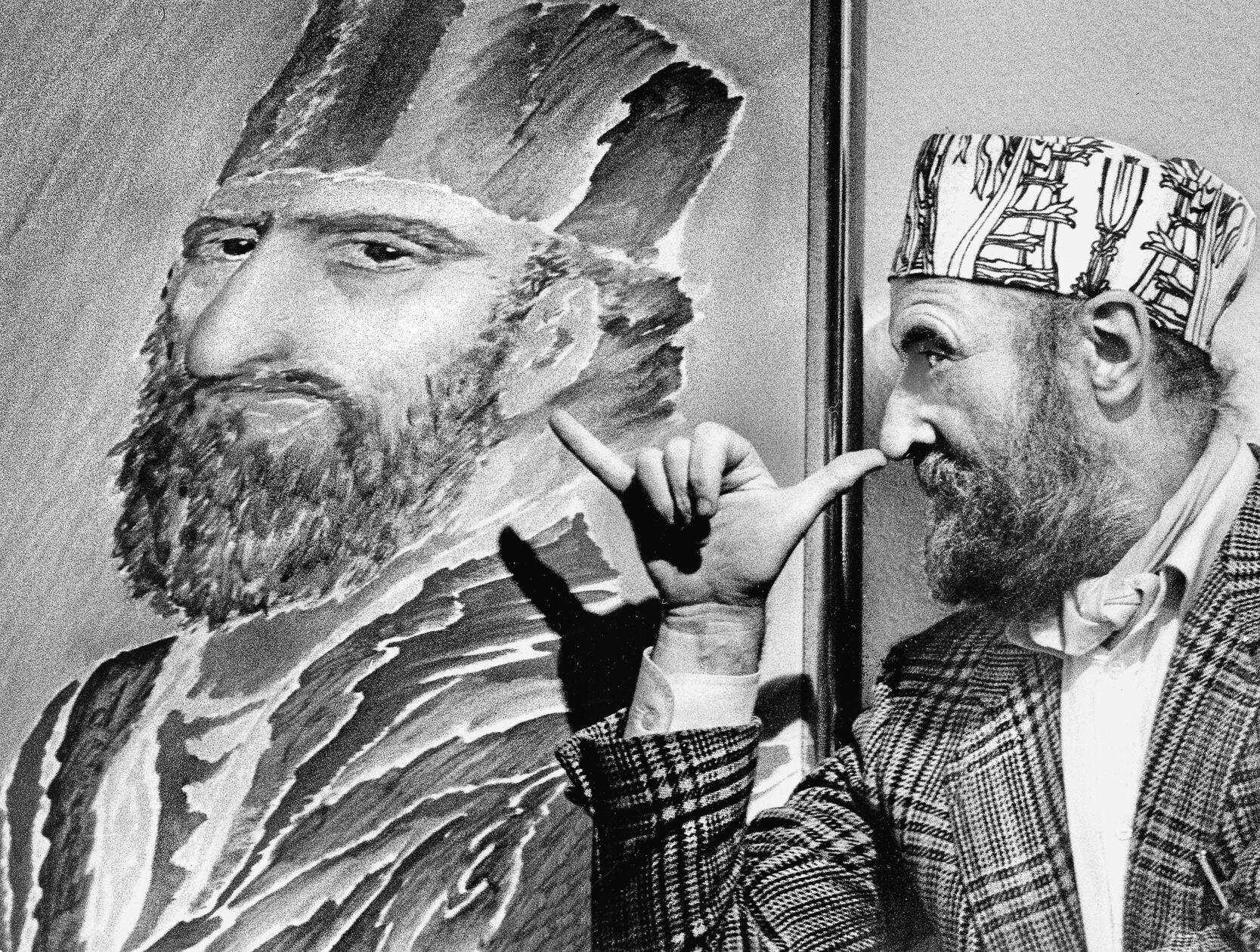 Ein hoher Besuch aus der zeitgenössischen Kunstwelt beehrte Nürnberg im Oktober 1985. Die Kaiser-Galerie, damals gelegen in der Kaiserstraße 8, zeigte ältere druckgraphische Blätter und 21 neue Gemälde und Handzeichnungen von Ernst Fuchs, seines Zeichens bekanntester Vertreter der Wiener Schule des Phantastischen Realismus. Für unseren Fotografen posierte der exzentrische Künstler selbstironisch vor seinem eigenen Konterfei. Die Kappen, welche der sich barock gebende Malerfürst stets trug, gestaltete er selbst.