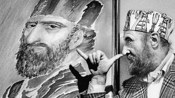 Ein hoher Besuch aus der zeitgenössischen Kunstwelt beehrte Nürnberg im Oktober 1985. Die Kaiser-Galerie, damals gelegen in der Kaiserstraße 8, zeigte ältere druckgraphische Blätter und 21 neue Gemälde und Handzeichnungen von Ernst Fuchs, seines Zeichens bekanntester Vertreter der Wiener Schule des Phantastischen Realismus. Für unseren Fotografen posierte der exzentrische Künstler selbstironisch vor seinem eigenen Konterfei. Die Kappen, welche der sich barock gebende Malerfürst stets trug, gestaltete er selbst.