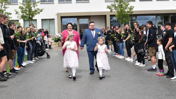 Im festlich geschmückten Trausaal der Gemeinde Pilsach gaben sich Barbara Sendlbeck und Marcel Reitmeier das Ja-Wort. Die standesamtliche Trauung wurde von Pilsachs erstem Bürgermeister Andreas Truber vollzogen. Barbara, 36 Jahre alt und aus Pilsach, und Marcel, 38, aus Dresden, lernten sich online kennen. Seit einiger Zeit leben sie gemeinsam in Pilsach. Die Braut arbeitet als Sachbearbeiterin, während der Bräutigam derzeit eine Umschulung zum Fachinformatiker für Systemintegration absolviert. Auf das frischvermählte Paar wartete sich ein langes Spalier: Mit dabei waren die Büsara Budn und der Kirwaverein Büsa – zwei Vereine, in denen die Braut verwurzelt ist. Auch ihre Mädelsclique empfing sie mit begeistertem Applaus.