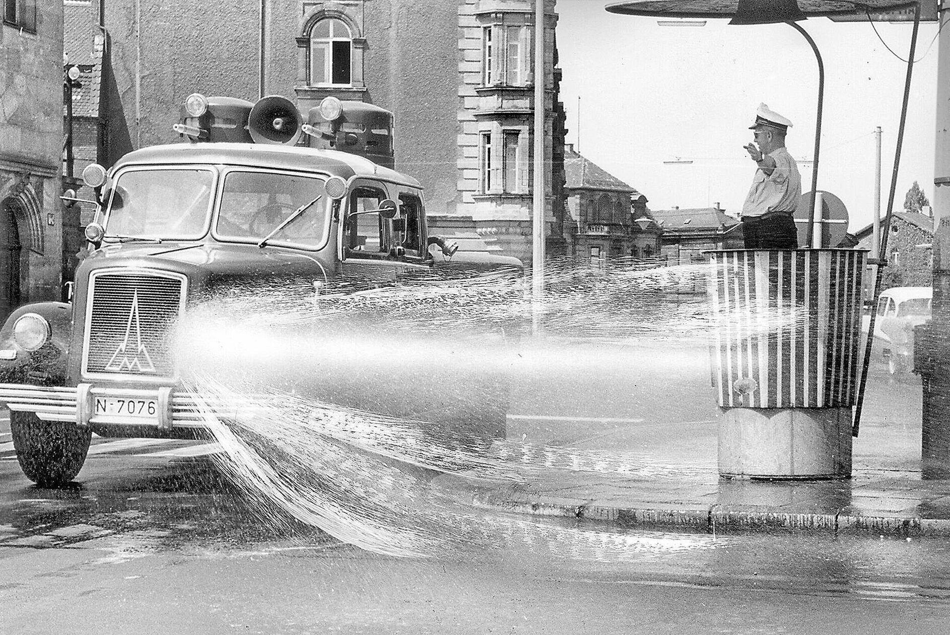 Wie ein Geschenk des Himmels betrachtete der Verkehrspolizist am Plärrer den Polizei-Wasserwerfer, der im Juli 1957 bei Temperaturen bis zu 38 Grad im Schatten eine erfrischende Dusche in seine Richtung schickte. Um den glühend heißen Asphalt etwas abzukühlen, drehte der Wasserwerfer der Polizei im Abstand von einer halben Stunde Runden um die Verkehrskanzel des schwitzenden Kollegen, bespritzte die dampfende Straße - und nebenbei auch ihn selbst ein wenig - mit wohltuend kühlem Nass.