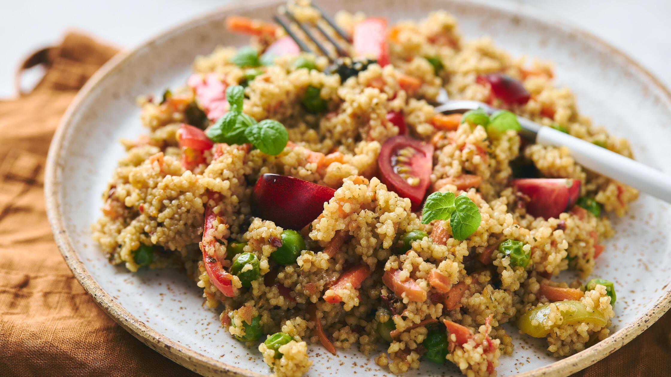 Vegan warm salad made with couscous, tomatoes, gre