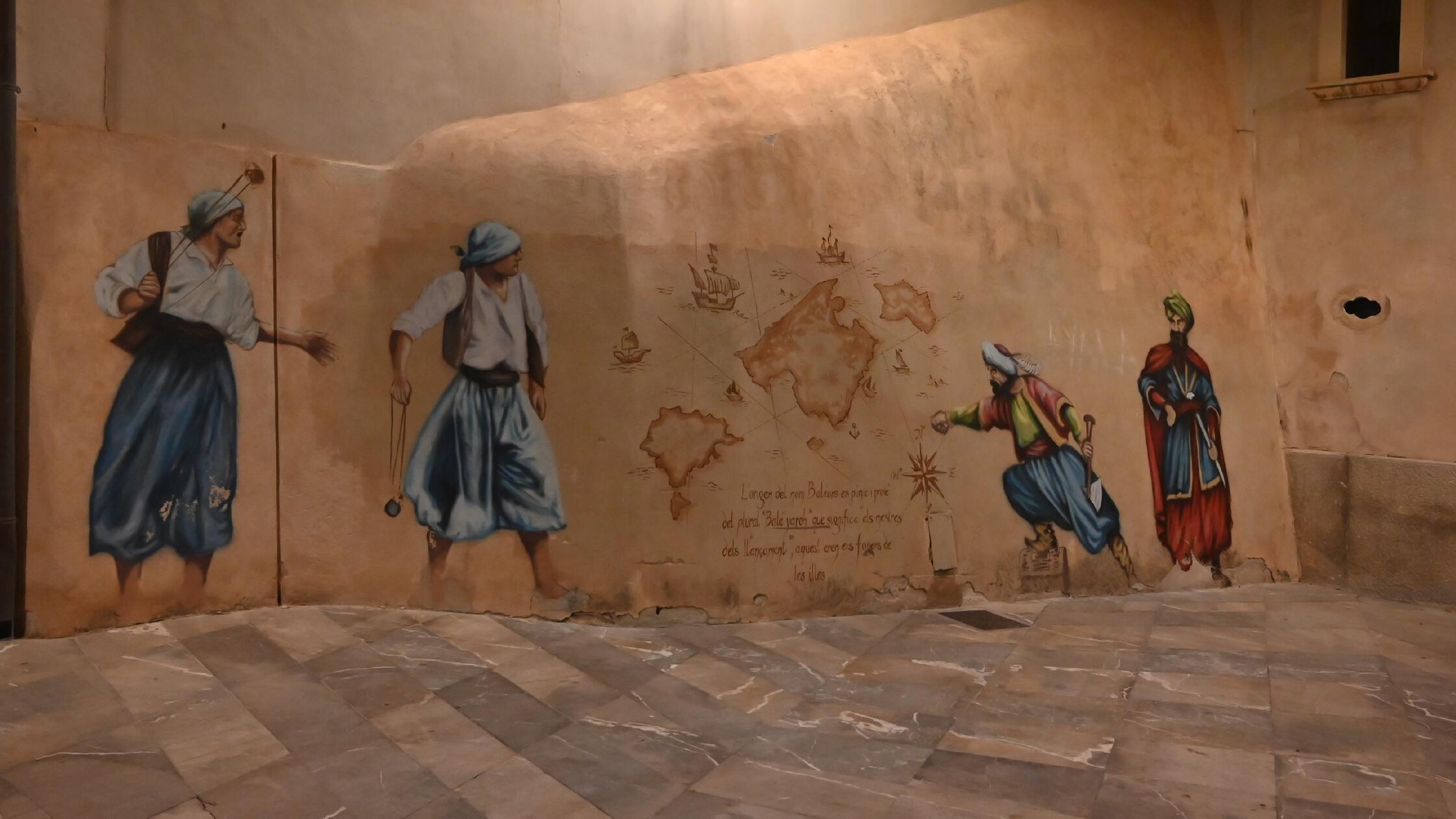 Eindrücke aus Palma, der Hauptstadt von Mallorca: Der Name der Inselgruppe Balearen leitet sich von einem altgriechischen Wort ab, welches „werfen“bedeutet. In der Antike gefürchtet kamen von den Inseln die Steinschleuderer Els Foners Balears, die sich als Söldner auf den Kriegsschauplätzen der Antike verdingten. Dieses Wandbild nahe der Kathedrale erinnert an die Namensgeber mit ihren Steinschleudern.