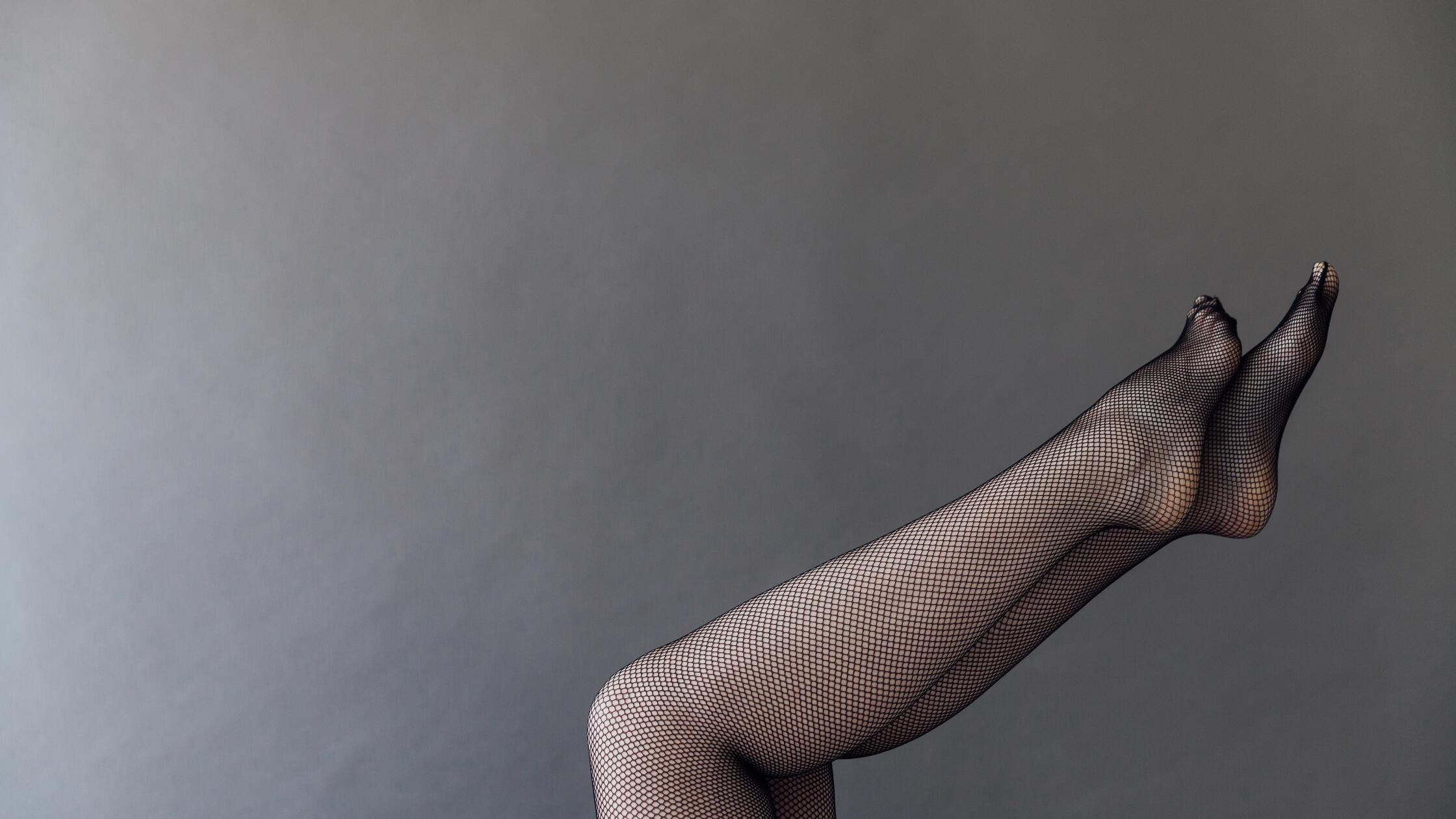 women's feet in tights in net on a gray background