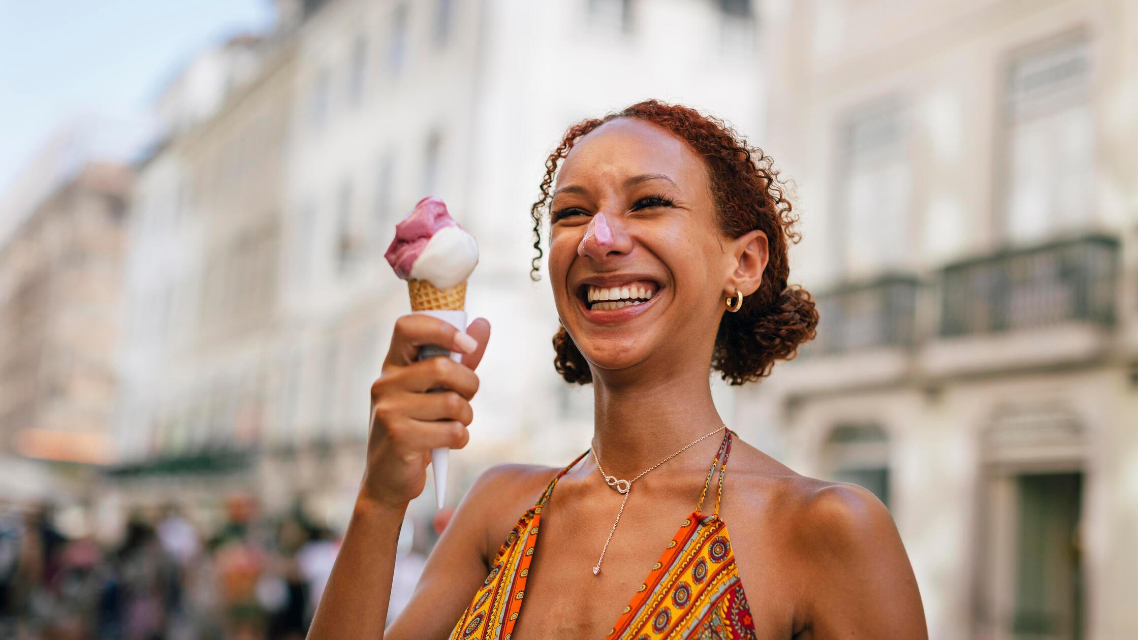 Cheerful young woman with curly hair enjoying ice 