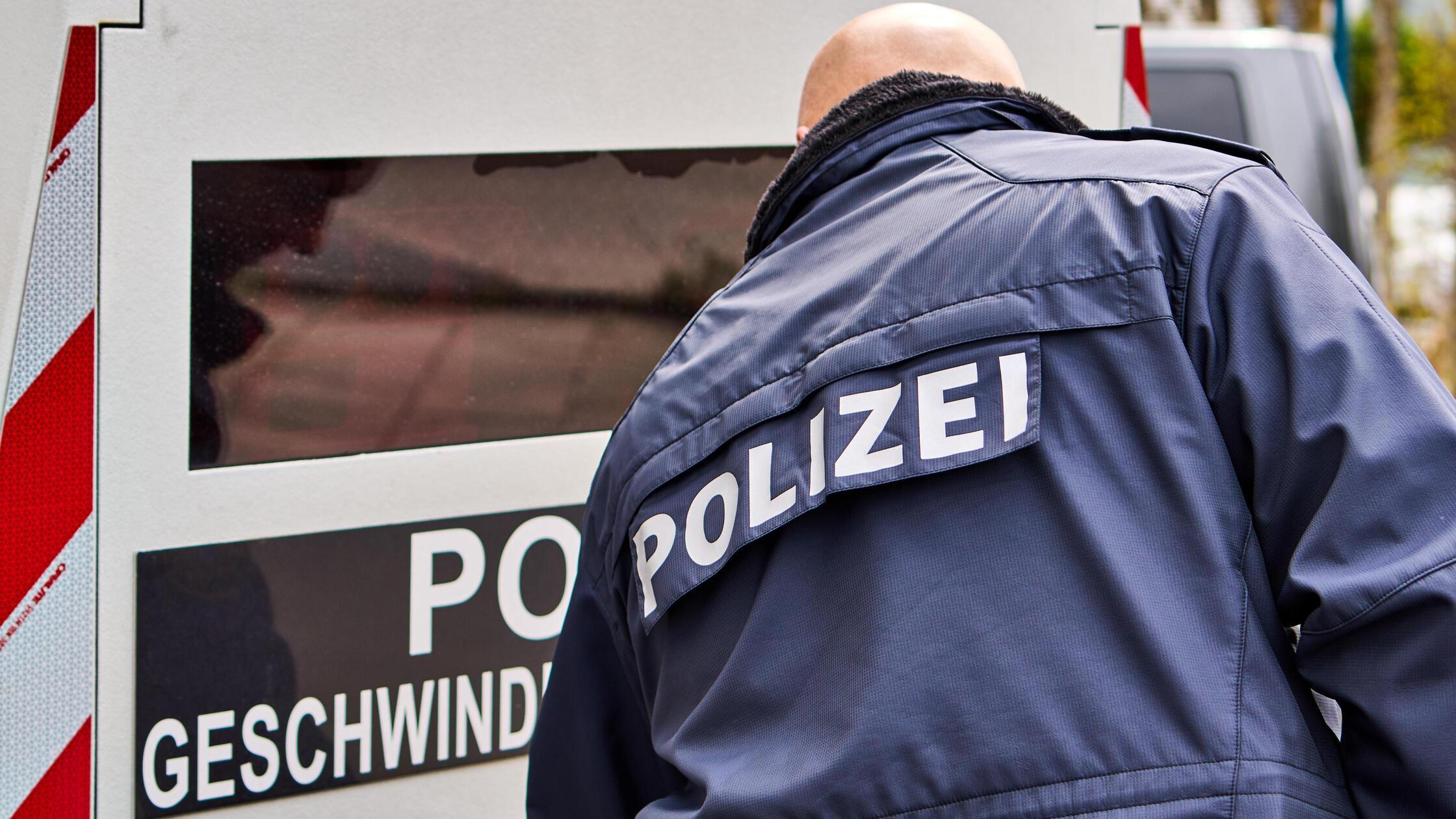 Ein Polizist in Uniform steht vor einem mobilen Bl