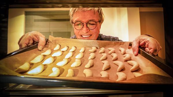 Weihnachtsplätzchen backen, Mann schiebt Backblech