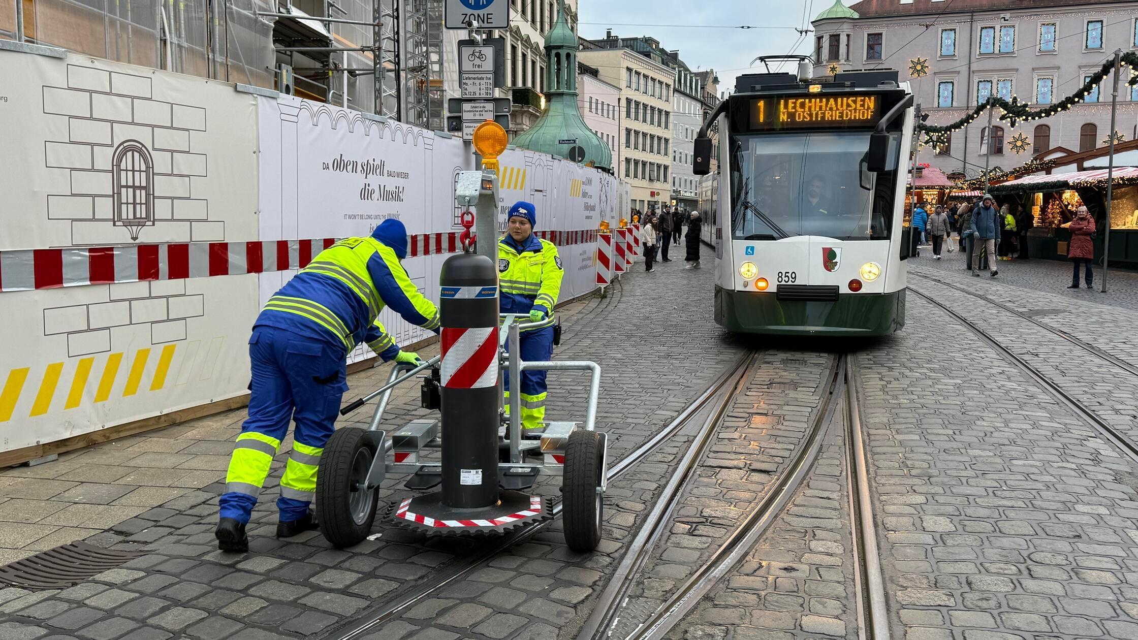 Ein Handwagen rollt heran, zwei Sicherheitskräfte 