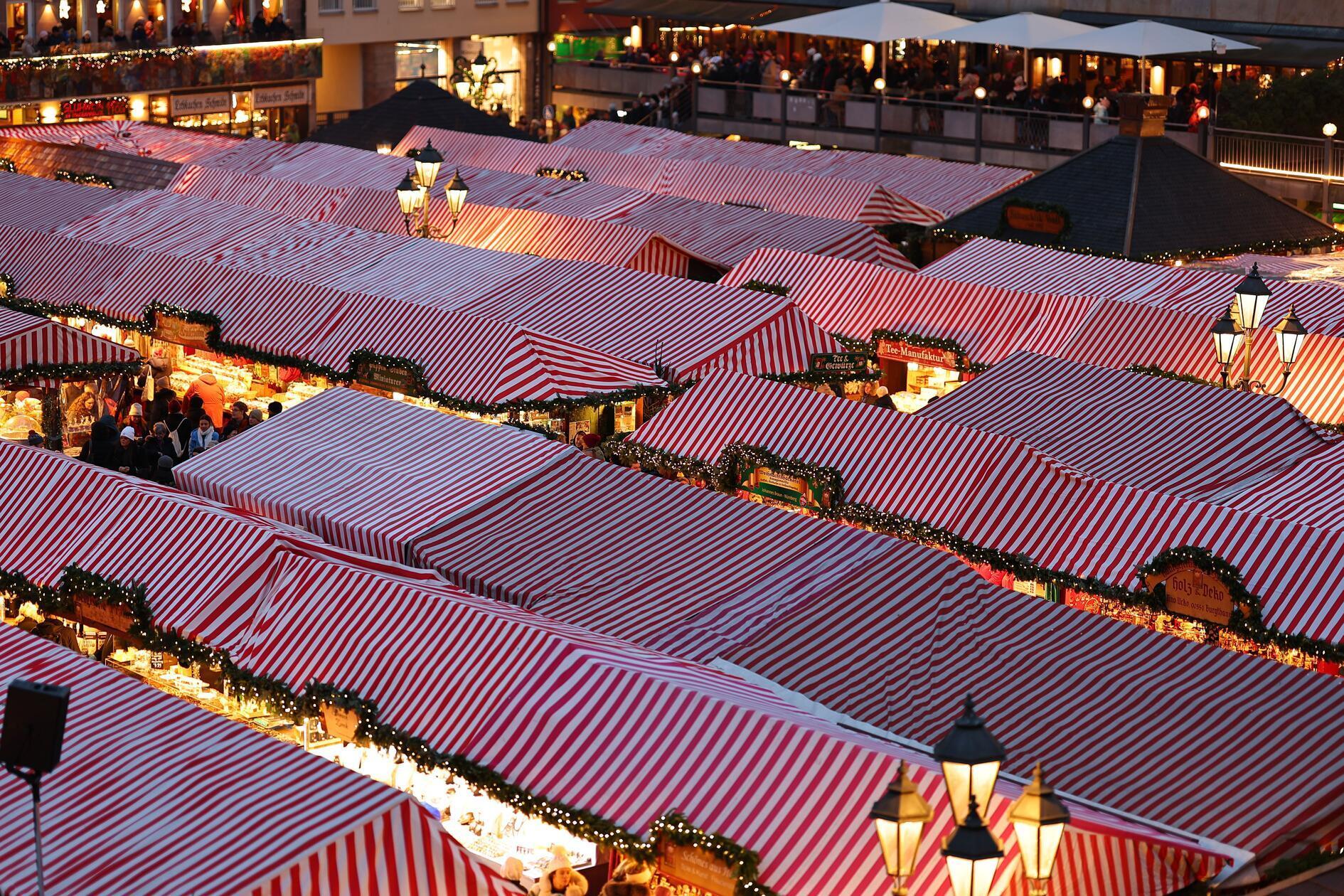 ... und die Leute strömen im Lichtermeer zwischen den Glühwein und Köstlichkeiten umher.