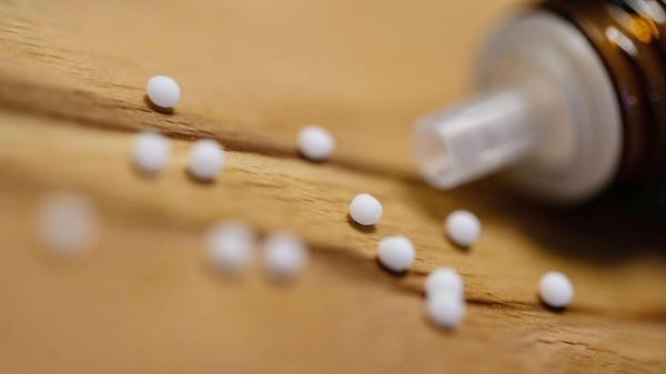 Kügelchen eines homöopathischen Mittels liegen neb